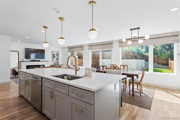 a kitchen with kitchen island a stove a sink a dining table and chairs