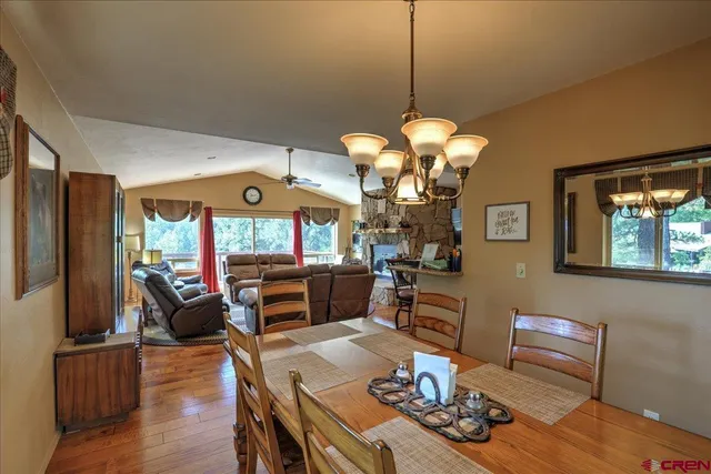 a dining room with wooden floor a chandelier a wooden table and chairs