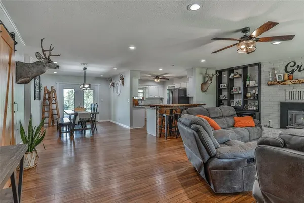a living room with furniture kitchen view and a wooden floor