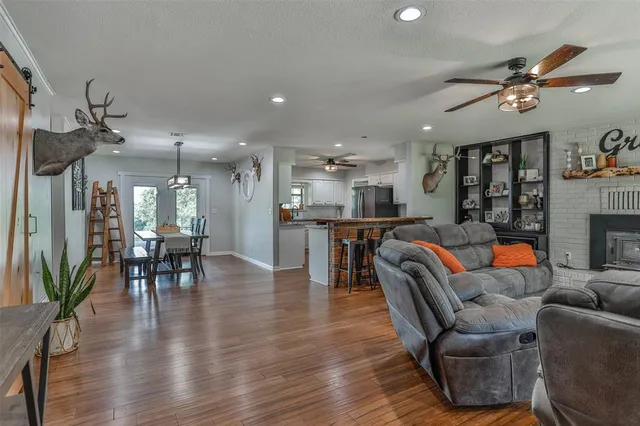 a living room with furniture kitchen view and a wooden floor