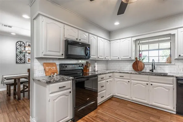 a kitchen with kitchen island granite countertop a sink cabinets and stainless steel appliances