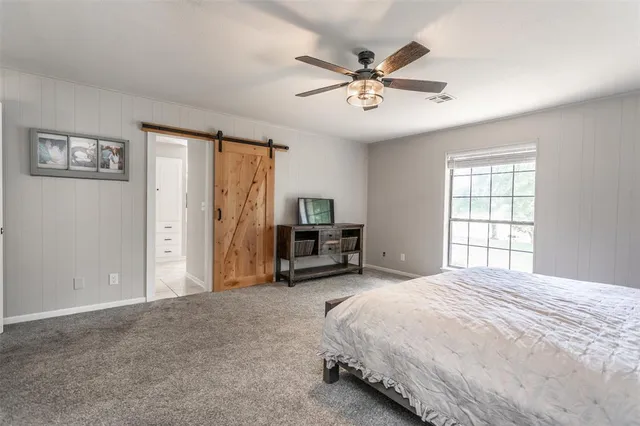 a spacious bedroom with a bed a dresser and a chandelier