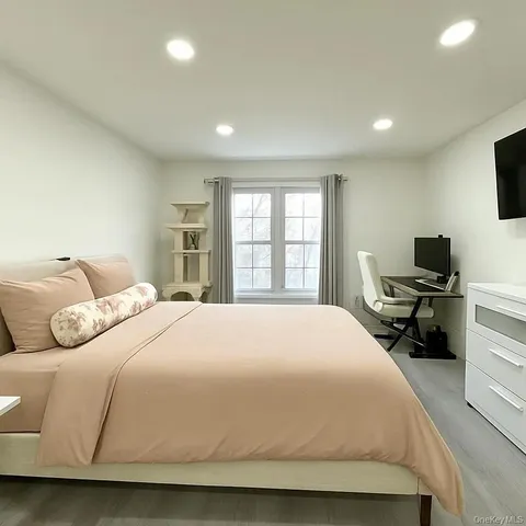 a bedroom with a bed a large window and a television