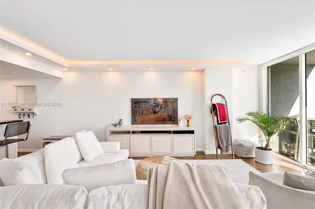 a living room with furniture kitchen view and a flat screen tv