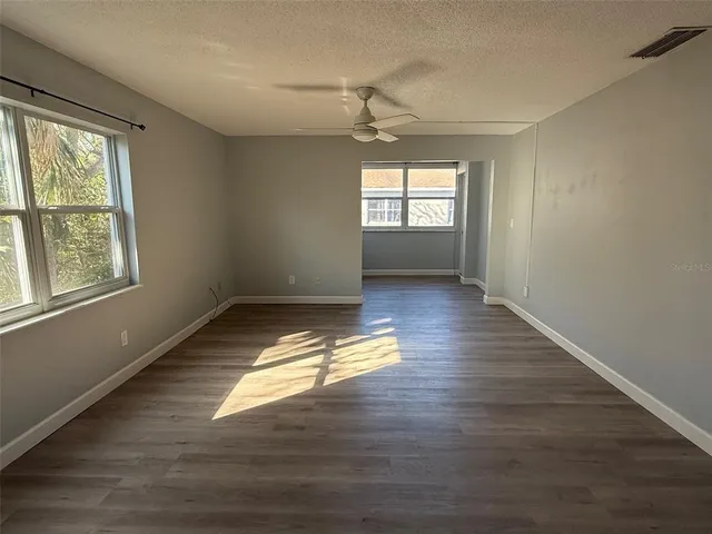 a view of empty room with wooden floor and fan