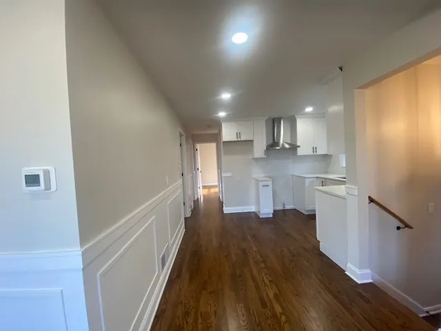 a kitchen with stainless steel appliances granite countertop a refrigerator a sink dishwasher a stove and white countertops with wooden floor