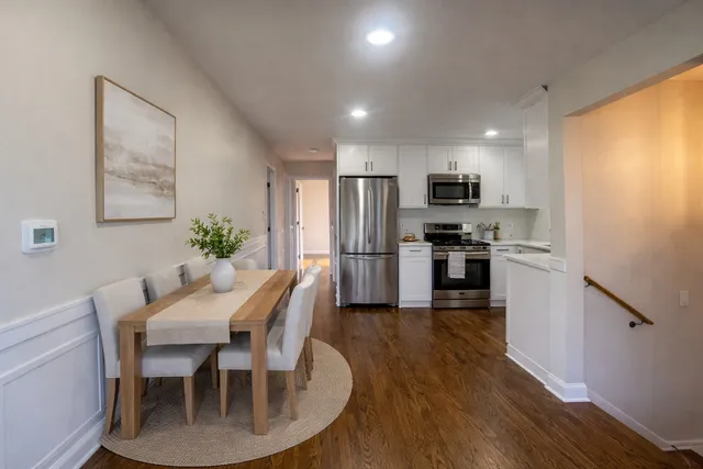 a kitchen with granite countertop stainless steel appliances a dining table and chairs