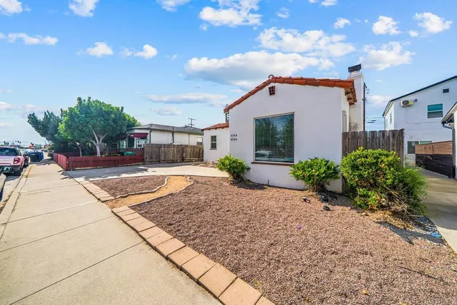 a front view of a house with a yard and potted plants