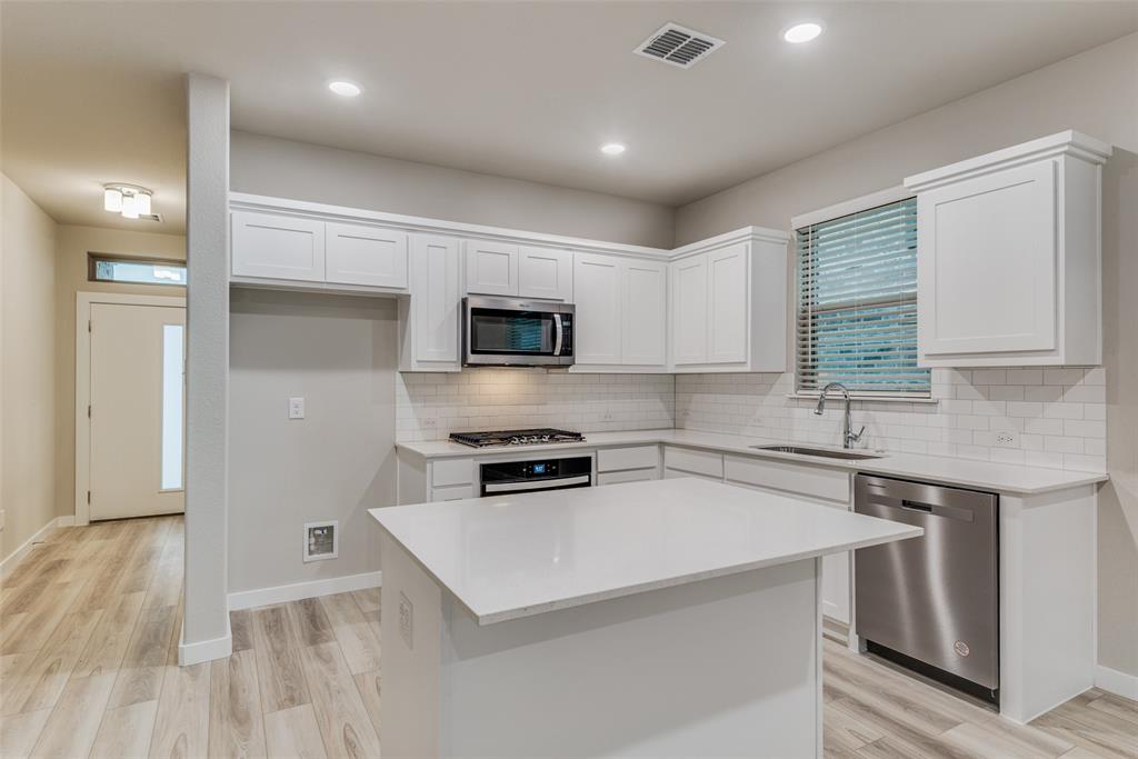 2544 Rambling Road Celina, TX 75009 - Photo 8 of 25 Kitchen featuring a kitchen island, light wood-type flooring, stainless steel appliances, white cabinets, and sink