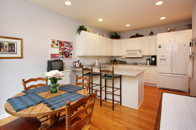 1760 Park Ridge Point, Unit 1760 Park Ridge, IL 60068 - Photo 6 of 15 a kitchen with stainless steel appliances granite countertop a stove a refrigerator a kitchen island a dining table and chairs with wooden floor