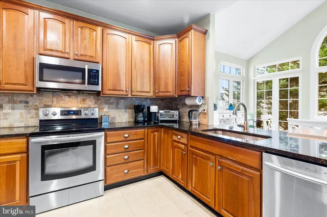 a kitchen with stainless steel appliances granite countertop a stove a sink and a microwave
