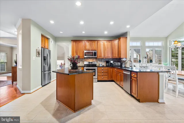a large kitchen with stainless steel appliances kitchen island granite countertop a refrigerator and a sink