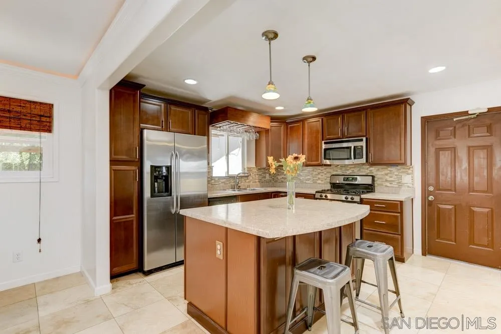 4925 Rebel Road San Diego, CA 92117 - Photo 10 of 25 a kitchen with stainless steel appliances kitchen island granite countertop a refrigerator a stove a oven a sink a dining table and chairs with wooden floor