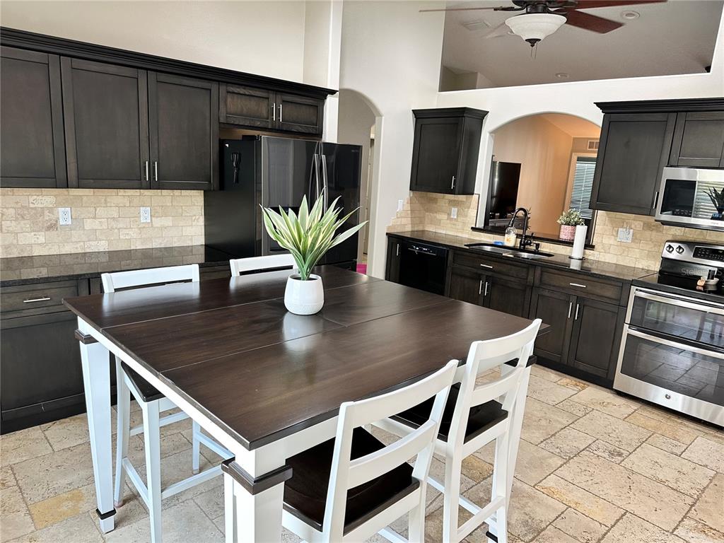 7 Lancaster Lane Palm Coast, FL 32137 - Photo 5 of 67 a kitchen with stainless steel appliances kitchen island granite countertop a table chairs and a refrigerator