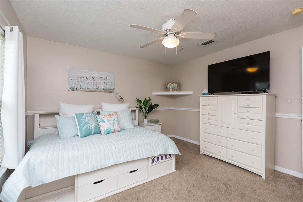 7 Lancaster Lane Palm Coast, FL 32137 - Photo 58 of 67 a bedroom with a bed a mirror and a flat screen tv