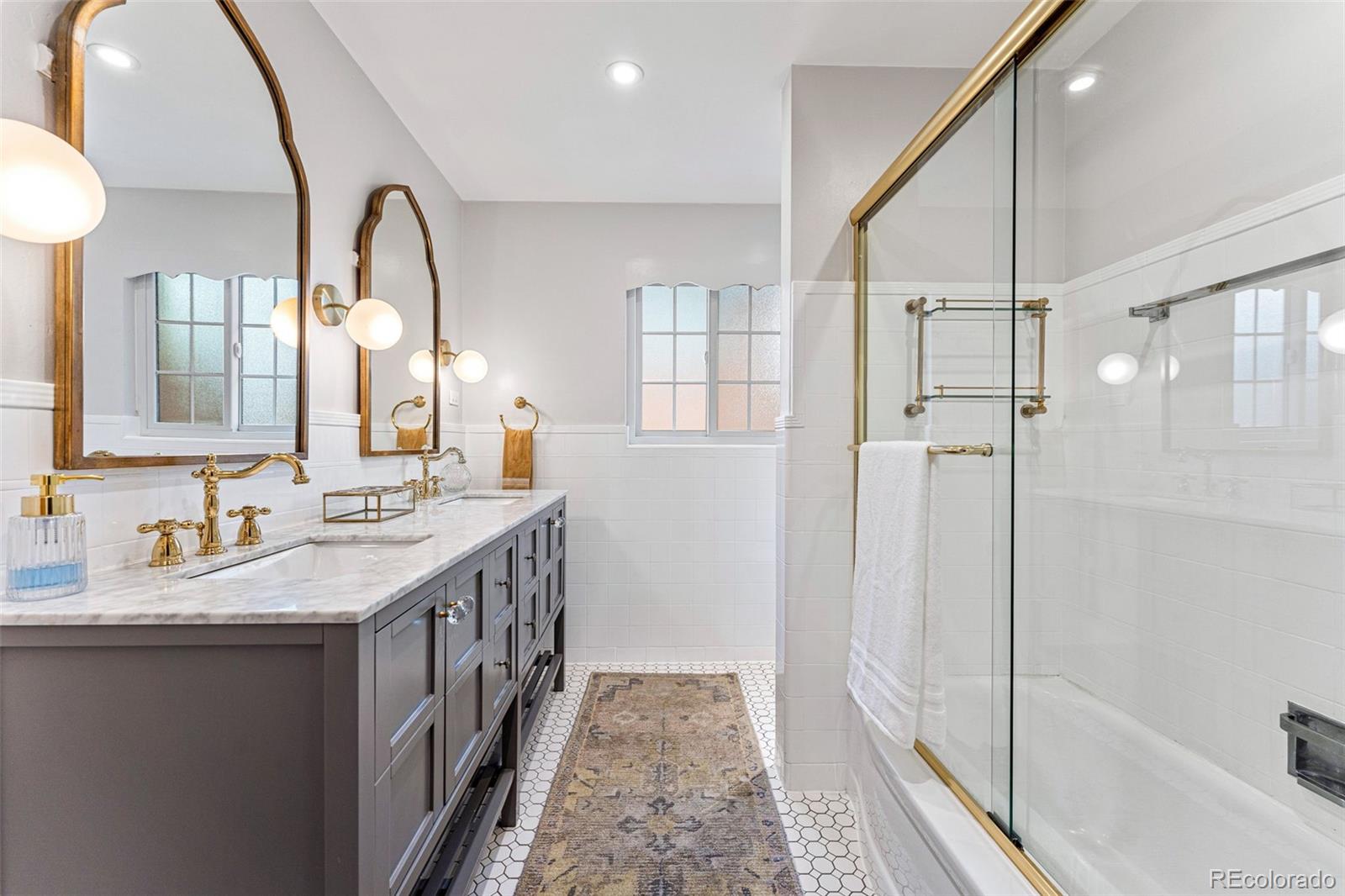 3715 Fenton Street Wheat Ridge, CO 80212 - Photo 7 of 13 a bathroom with a double vanity sink a mirror and a shower