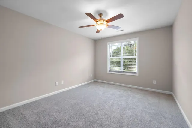 an empty room with window and ceiling fan