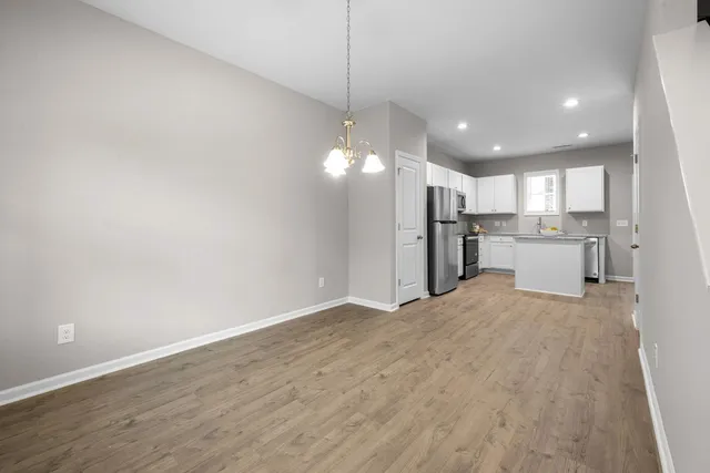 a open kitchen with a refrigerator a kitchen island a sink dishwasher a refrigerator and white cabinets with wooden floor