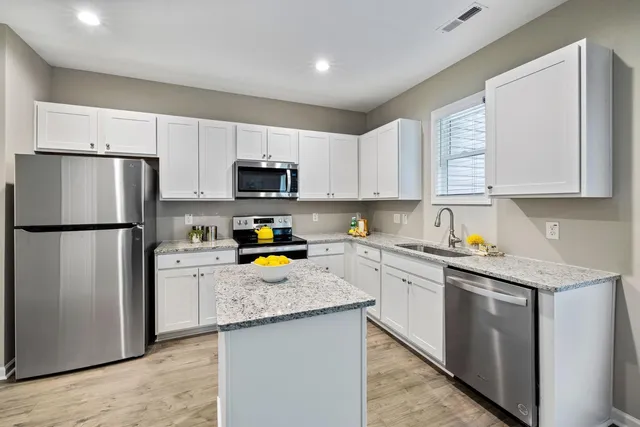 a kitchen with refrigerator a stove a sink cabinets and a window