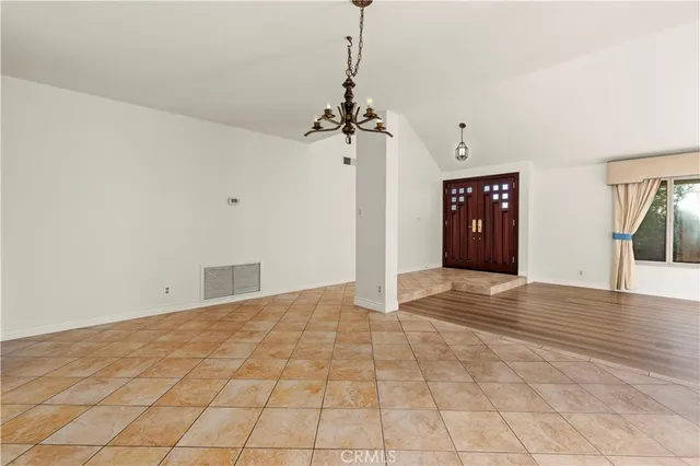 a view of an empty room with window and chandelier fan