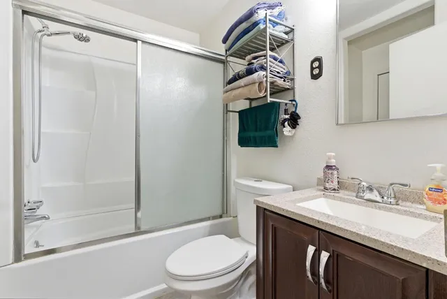 a bathroom with a granite countertop sink toilet and shower