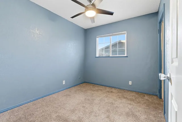an empty room with a window and a fan