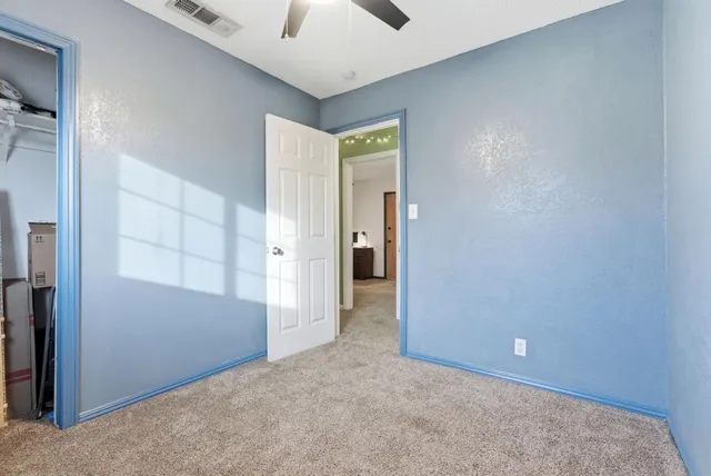 an empty room with closet and a chandelier fan