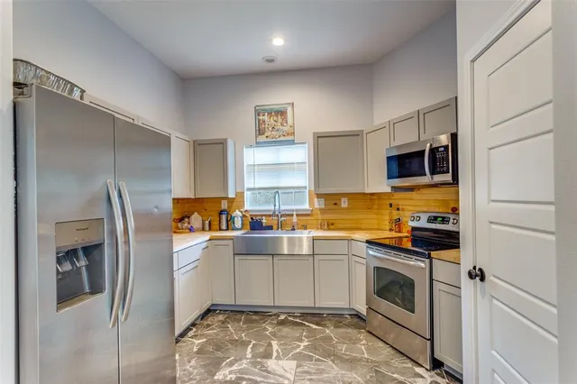 a kitchen with a sink stainless steel appliances and white cabinets