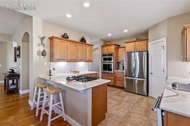 a kitchen with stainless steel appliances granite countertop a stove refrigerator and a sink