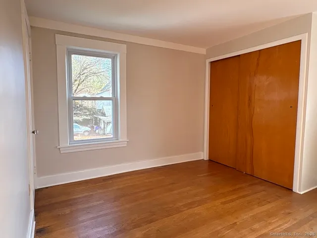 an empty room with wooden floor and windows with curtains