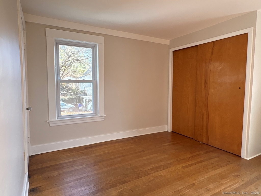 16 Tracy Street Thomaston, CT 06787 - Photo 15 of 26 an empty room with wooden floor and windows with curtains
