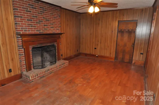 a view of an empty room with wooden floor and a fireplace