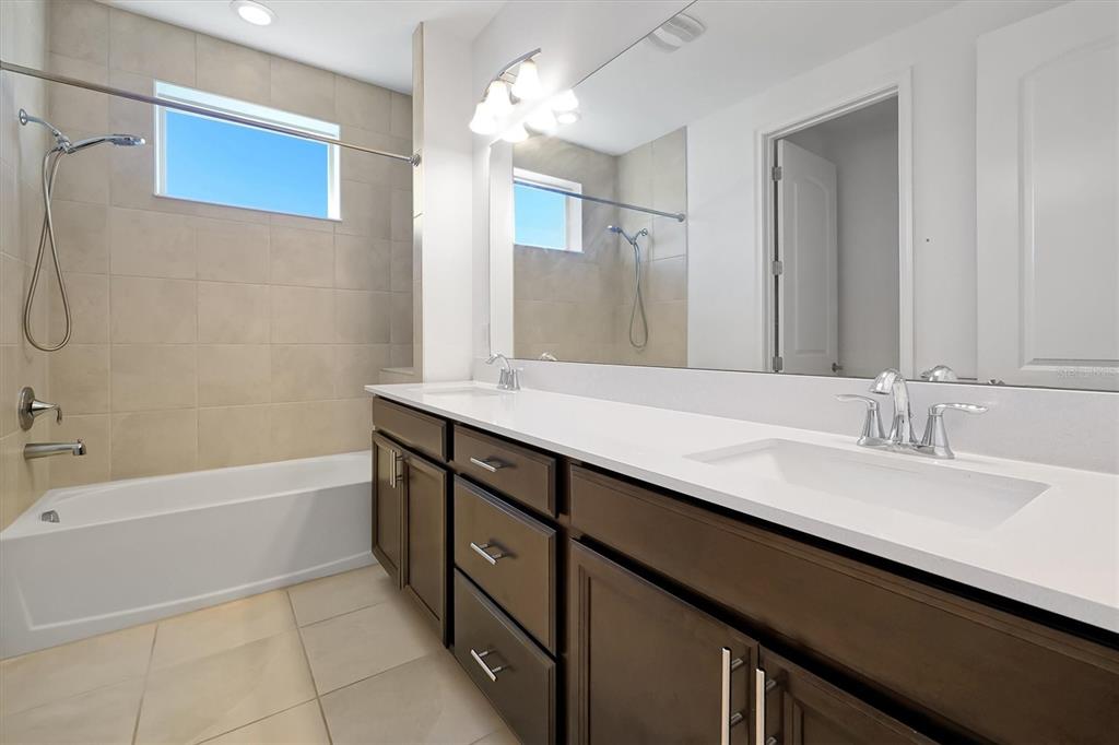 5200 Myrtleleaf Court St. Cloud, FL 34772 - Photo 30 of 59 a bathroom with a double vanity sink a mirror and a bathtub