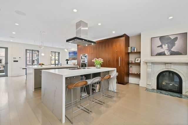 a kitchen with a sink dishwasher a fireplace with wooden cabinets and floor