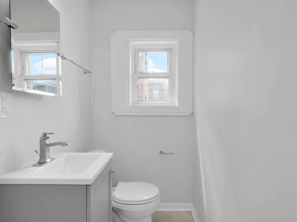 a bathroom with a toilet a sink a mirror and a window