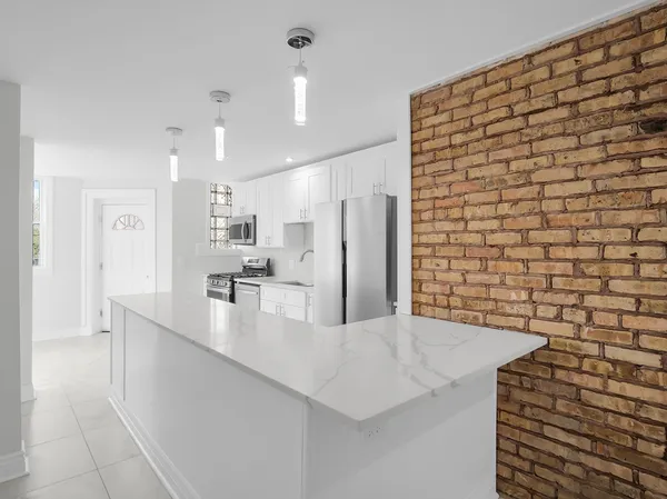 a large kitchen with stainless steel appliances a large counter top a stove and a refrigerator