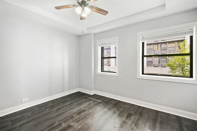 a view of empty room with wooden floor and fan