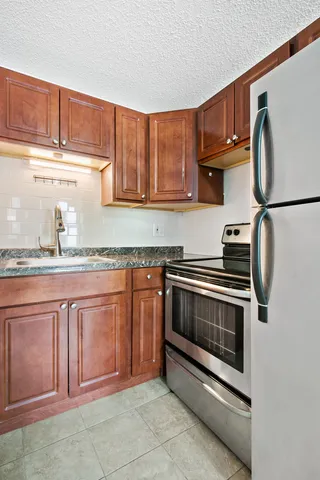 a kitchen with granite countertop a stove top oven cabinetry a sink and dishwasher