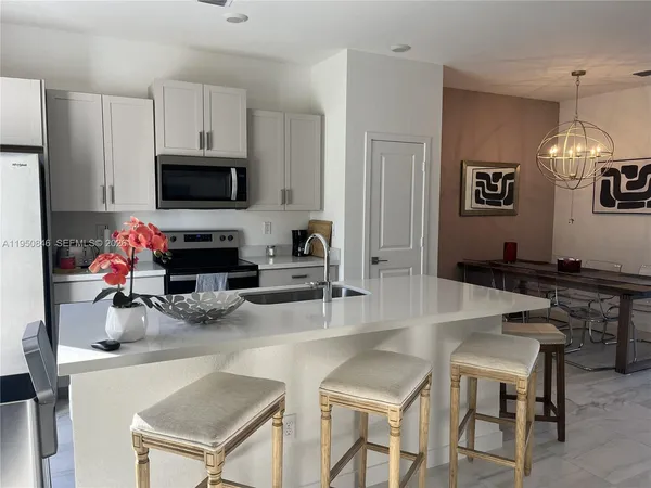 a kitchen with granite countertop a stove a sink a dining table and chairs
