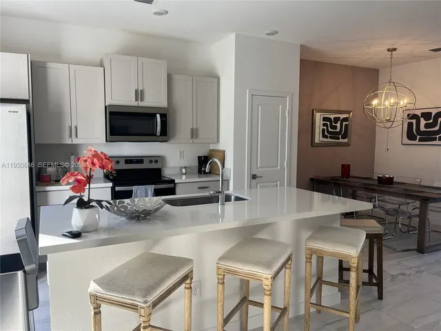 a kitchen with granite countertop a stove a sink a dining table and chairs
