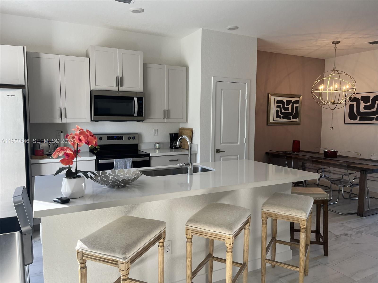 784 Southeast 19th Street, Unit 784 Homestead, FL 33034 - Photo 13 of 22 a kitchen with granite countertop a stove a sink a dining table and chairs