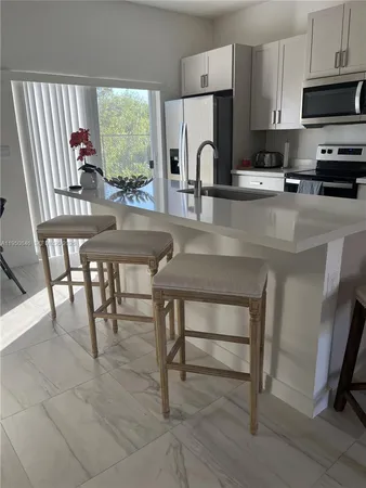 a kitchen with stainless steel appliances a table chairs microwave and sink