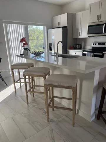 a kitchen with stainless steel appliances a table chairs microwave and sink