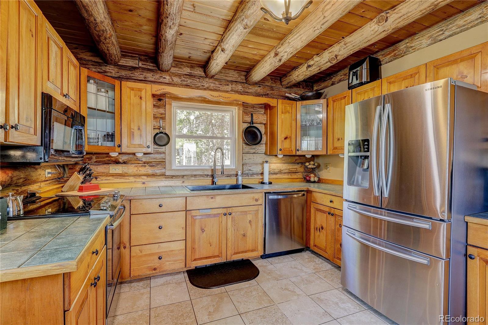 11142 Conifer Mountain Road Conifer, CO 80433 - Photo 21 of 50 a kitchen with stainless steel appliances granite countertop a refrigerator oven a sink dishwasher and white cabinets next to a window