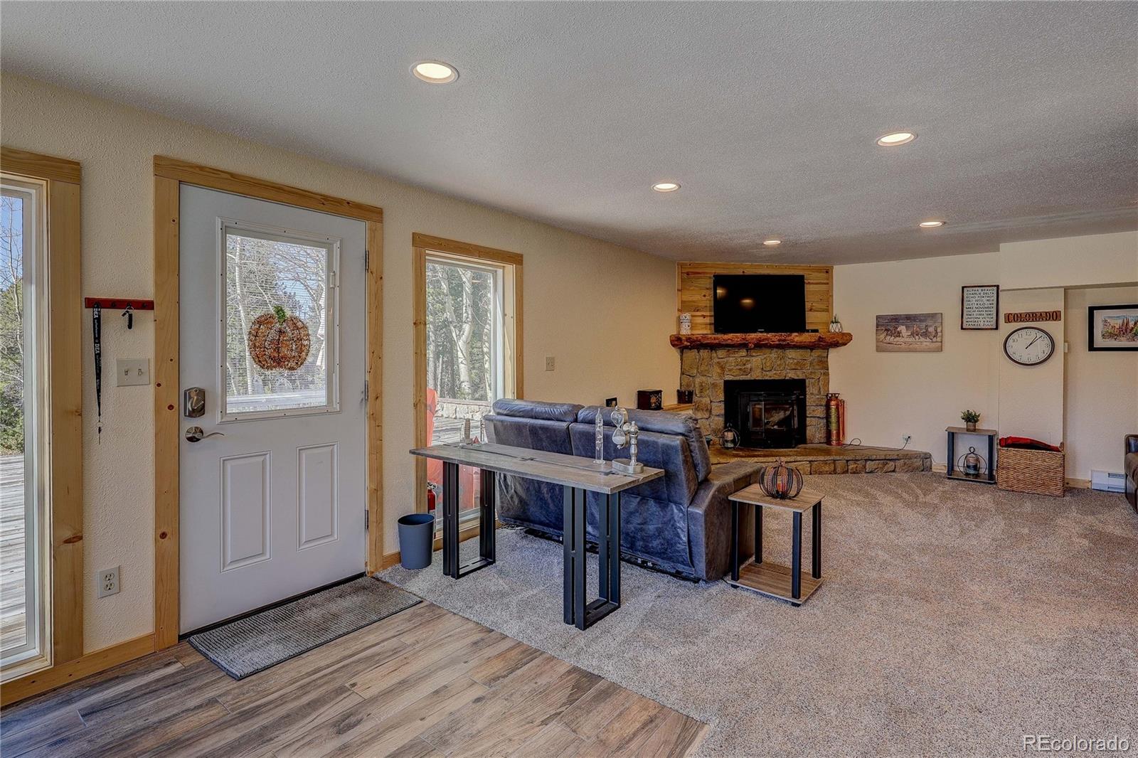 11142 Conifer Mountain Road Conifer, CO 80433 - Photo 30 of 50 a living room with furniture a fireplace and a flat screen tv