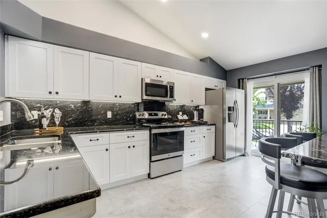 a kitchen with a stove a sink dishwasher a microwave oven and a stove with granite countertops