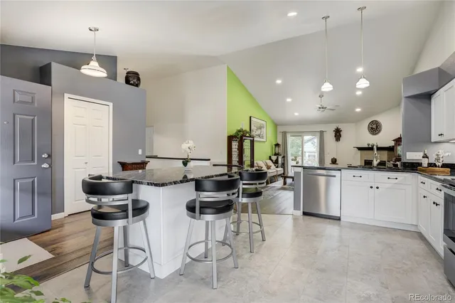 a kitchen with stainless steel appliances kitchen island granite countertop a stove a sink a dining table and chairs with wooden floor