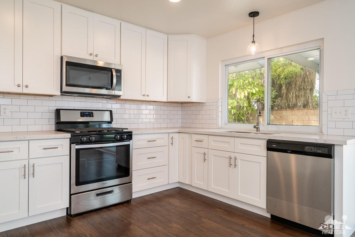 6987 Manhattan Drive Riverside, CA 92506 - Photo 1 of 28 a kitchen with granite countertop a stove a sink and a microwave