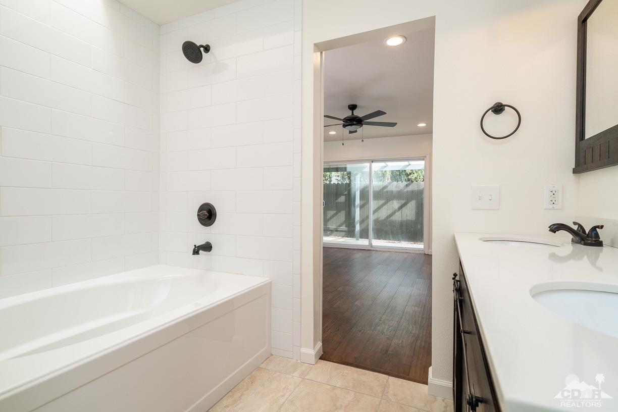 6987 Manhattan Drive Riverside, CA 92506 - Photo 15 of 28 a bathroom with a tub a sink and a large mirror
