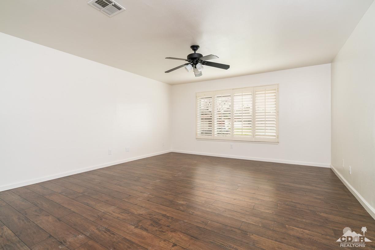 6987 Manhattan Drive Riverside, CA 92506 - Photo 18 of 28 an empty room with wooden floor ceiling fan and windows